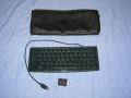 The newton keyboard and its travel pouch.  Also pictured is the adapter for the MessagePad 2000 to allow serial devices with a din-8 connector to connect. - mp2000-10.jpg